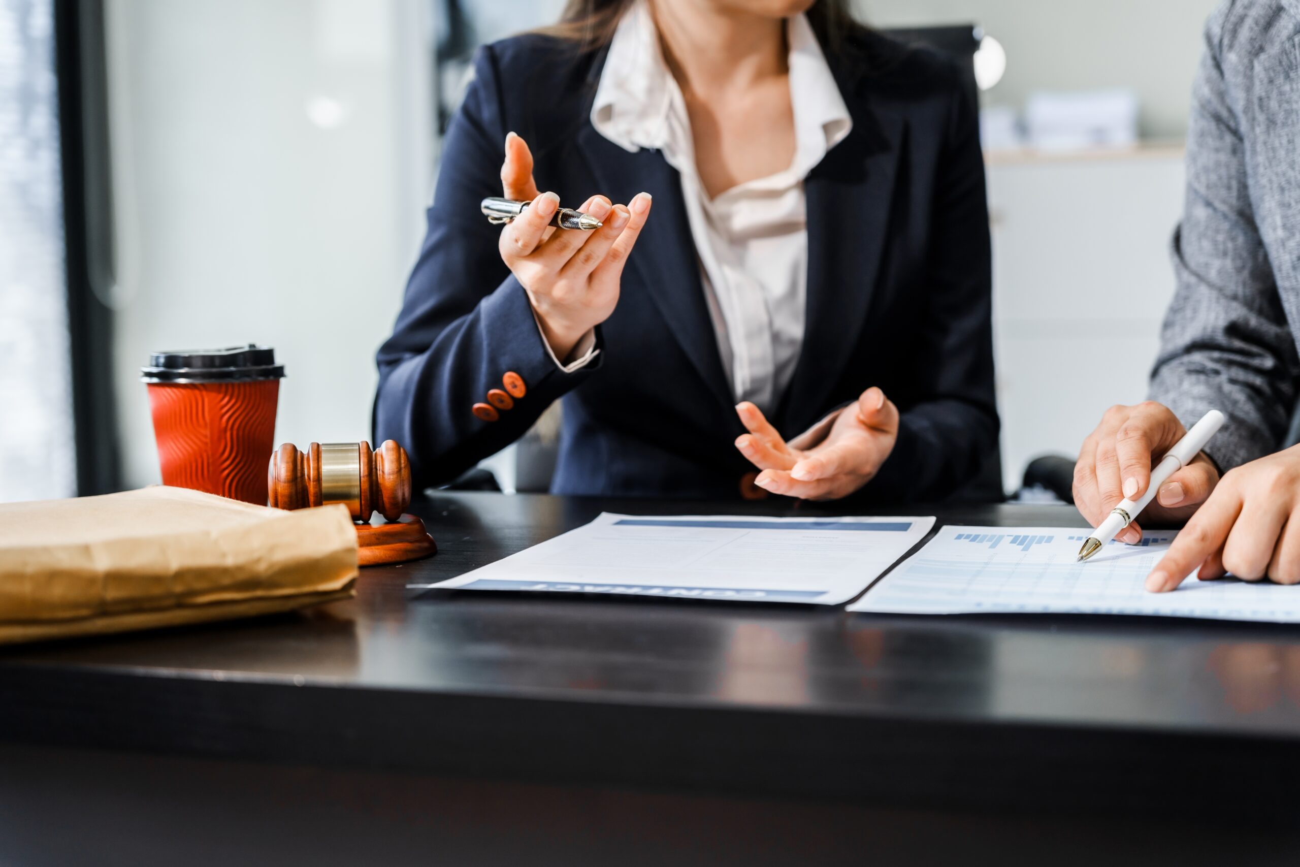 Two,Female,Lawyers,In,Business,Suits,Meet,At,Wooden,Desk,